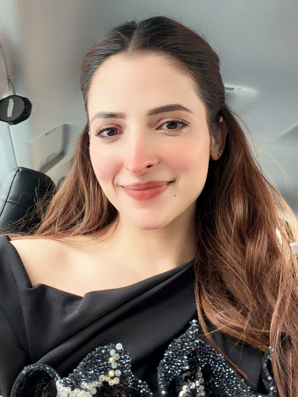 Smiling Pakistani celebrity Areeba Habib takes a car selfie in a sequined black saree, with long ...