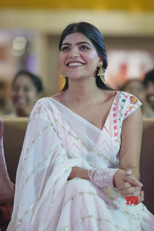 Candid portrait of smiling South Indian actress seated indoors in an embroidered white saree, loo...