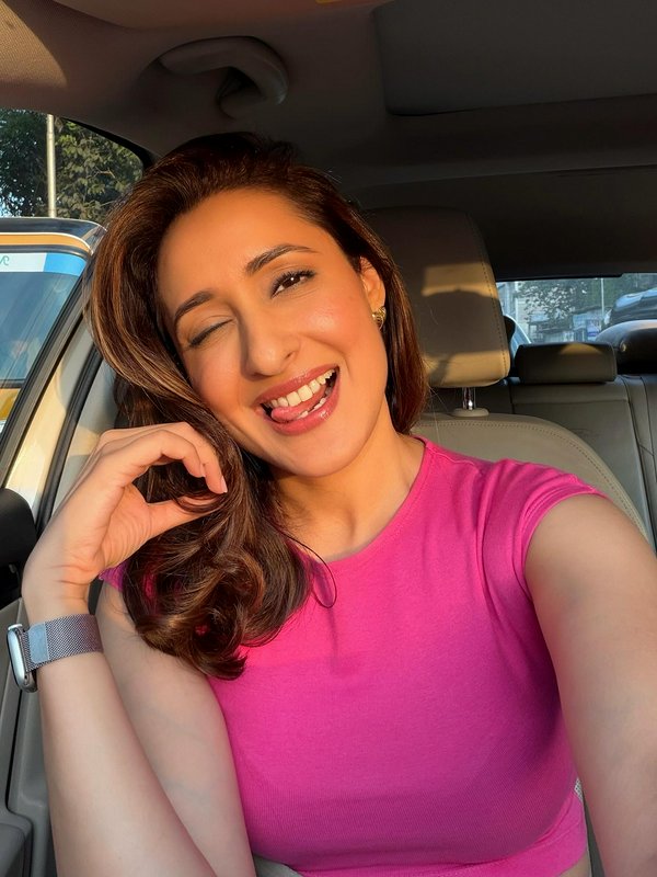 Playful woman winking and sticking out her tongue taking a cheerful sunny selfie while seated ins...