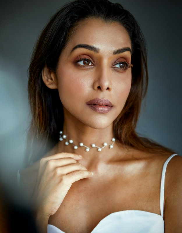 Studio beauty portrait of an elegant South Asian woman wearing a dainty pearl choker, soft moody ...