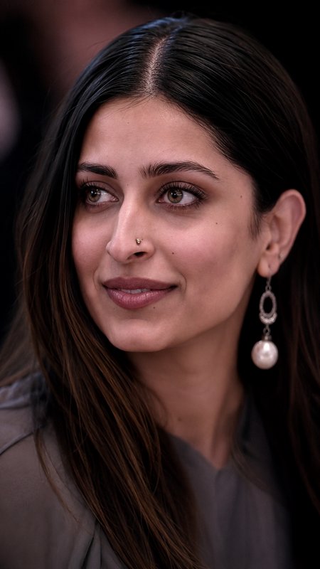 Close-up portrait of a South Asian woman with sleek dark hair, tiny nose stud, and pearl drop ear...