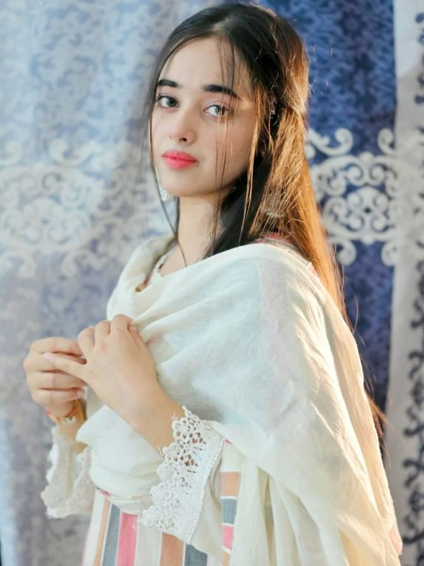 Portrait of young South Asian woman in lace-trimmed traditional wear, looking softly toward the c...