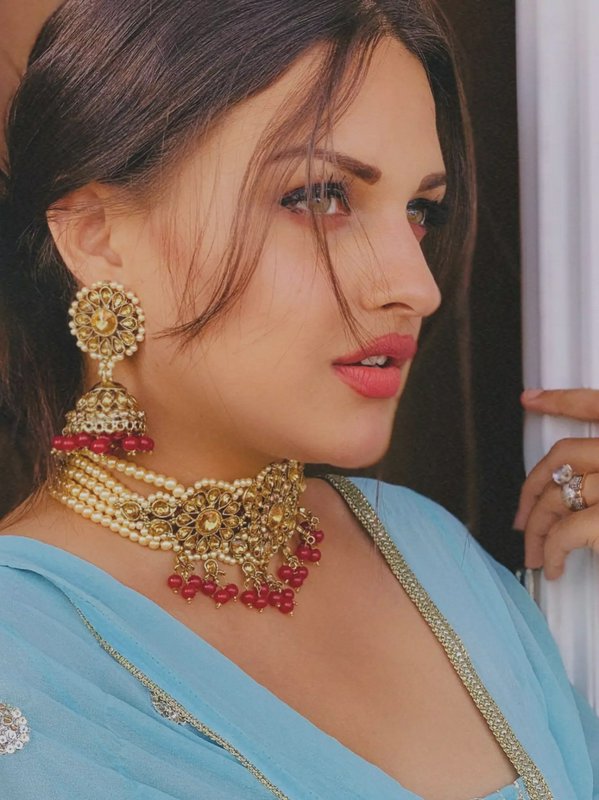 Close-up portrait of a woman wearing ornate Indian kundan jewelry and light blue traditional sare...