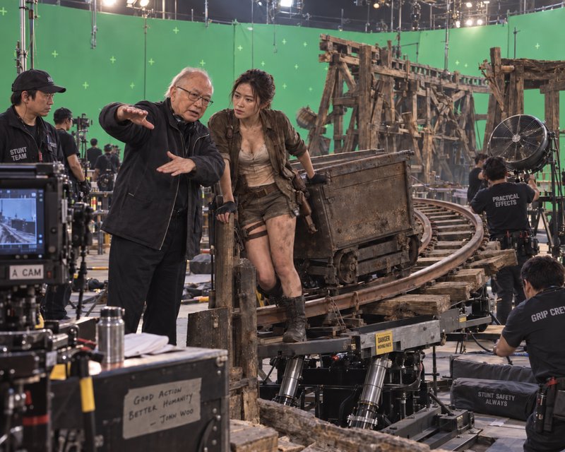 John Woo gives direction to an adventurer-costumed actress on a mine set soundstage
