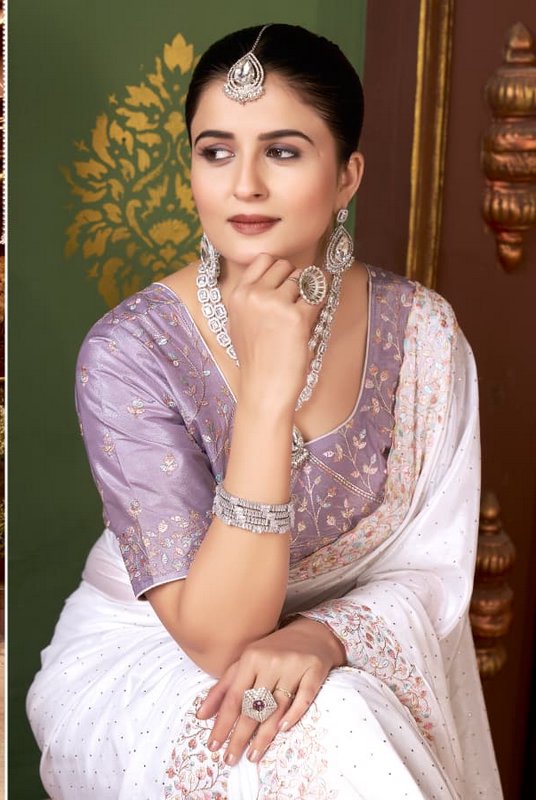 Elegant South Asian woman in embroidered saree wearing intricate kundan jewelry, posed against a ...
