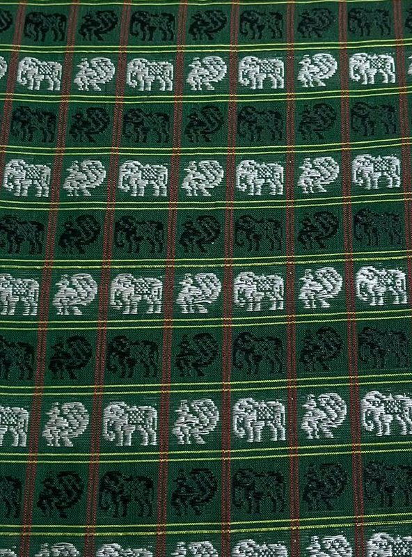 Close-up of dark green handwoven fabric with a repeating grid pattern of elephant and peacock motifs