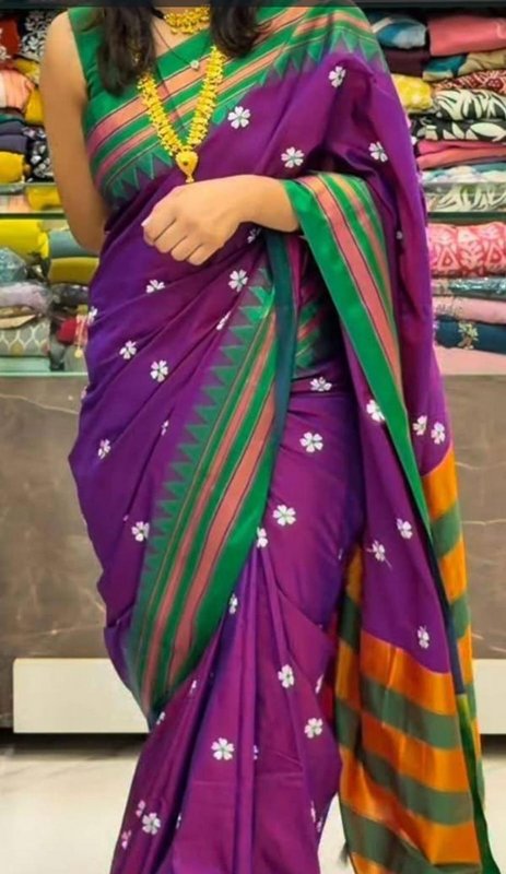 Model wearing a vibrant purple floral embroidered silk saree with a colorful striped border in a ...
