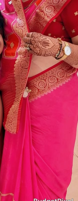 Close-up of woman in bright pink saree displaying intricate bridal henna mehndi on her jeweled hand