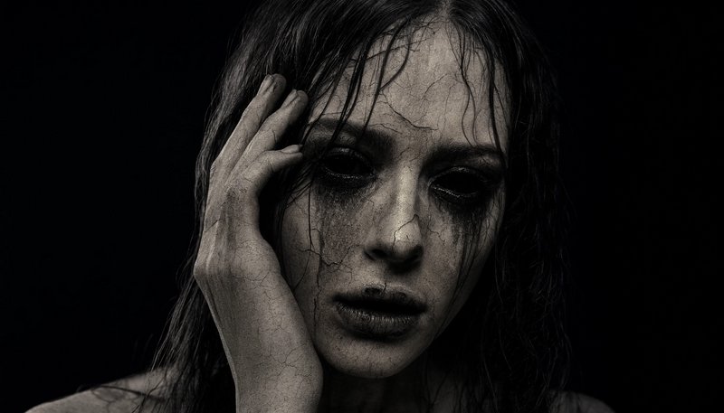 Close up horror portrait of a hollow-eyed ghostly woman with cracked skin, streaked dark makeup, ...