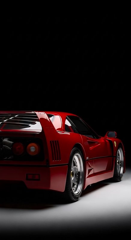 Dramatic rear three-quarter studio shot of a glossy red classic Ferrari F40 supercar against a bl...