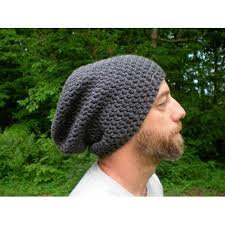 Profile view of a bearded man modeling a chunky slouchy gray knit beanie against a lush green woo...