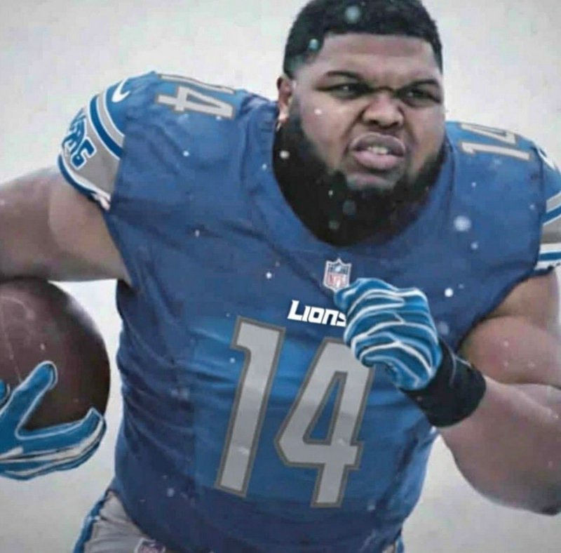 Intense Detroit Lions #14 NFL player carries a football while running through falling snow during...