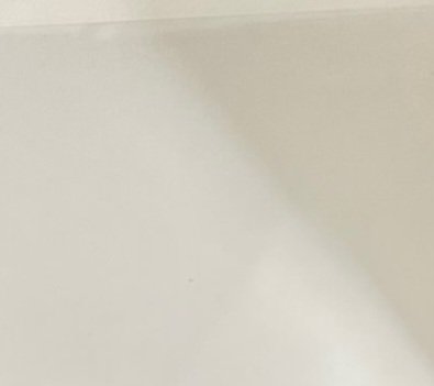 Close-up of a smooth matte off-white interior wall with soft curved shadow stretching across its ...