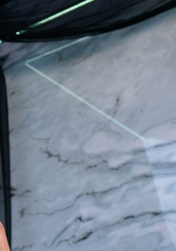 Laser level projected marking a cut line on a veined white marble slab in a stone fabrication wor...