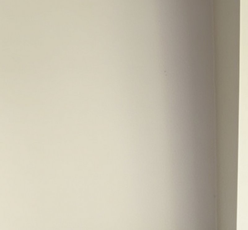 Plain smooth matte pale cream interior wall with soft shadow gradient, vertical door jamb edge on...