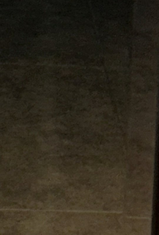 Dim low-light view of a textured warm brown stone wall with a vertical dark to light color gradient.