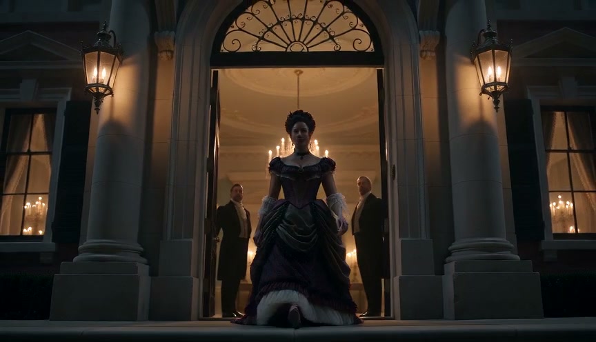 Woman in elaborate Victorian gown stands in grand manor doorway flanked by two formally dressed men