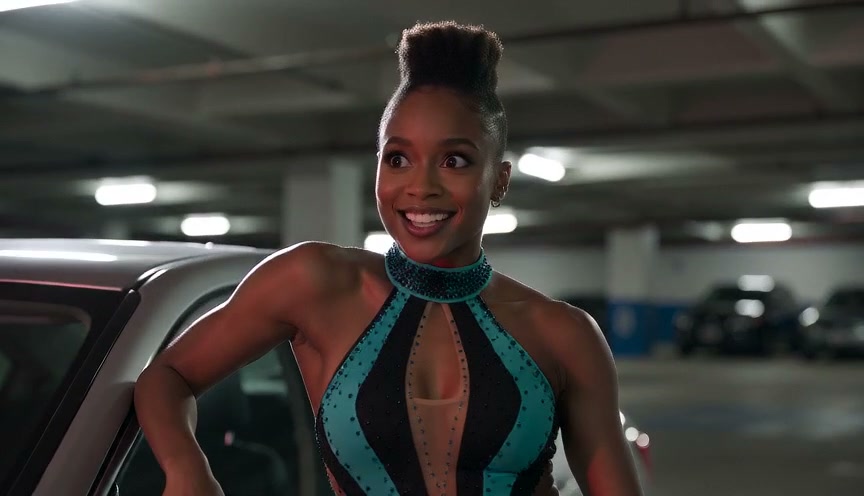 Smiling woman in a sparkling teal halter gown leans against a car in an underground parking garage