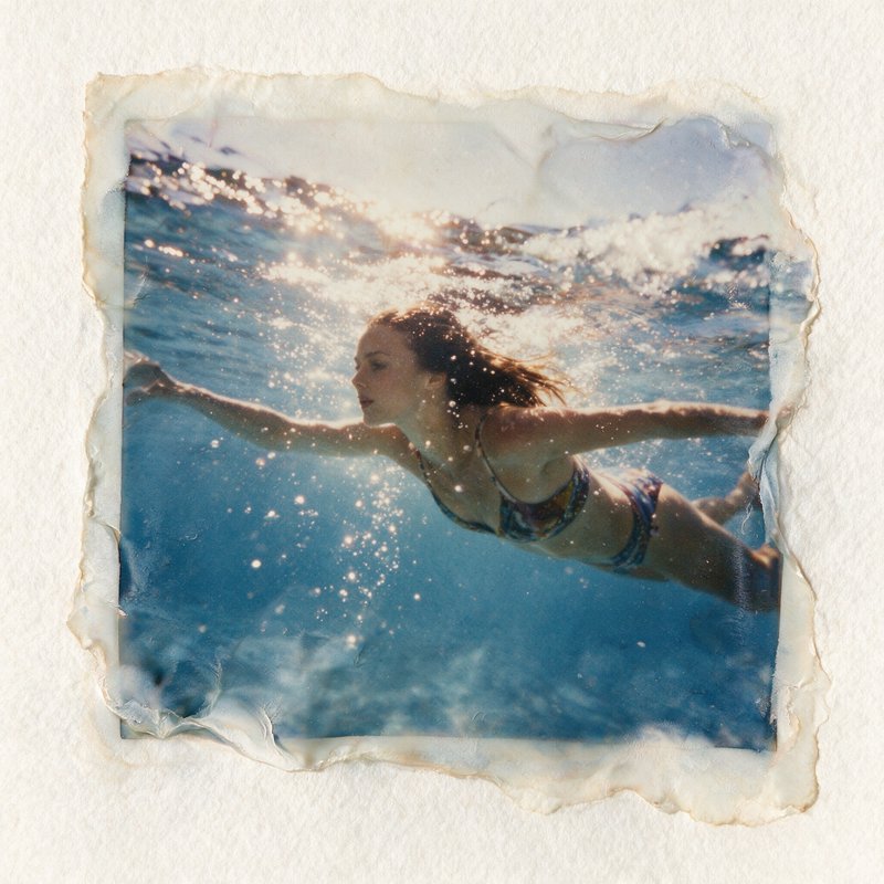 Torn vintage polaroid showing a woman swimming gracefully underwater in sunlit turquoise ocean, m...