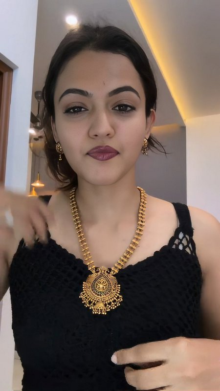 Close-up portrait of South Asian woman wearing ornate traditional gold temple jewelry indoors in ...