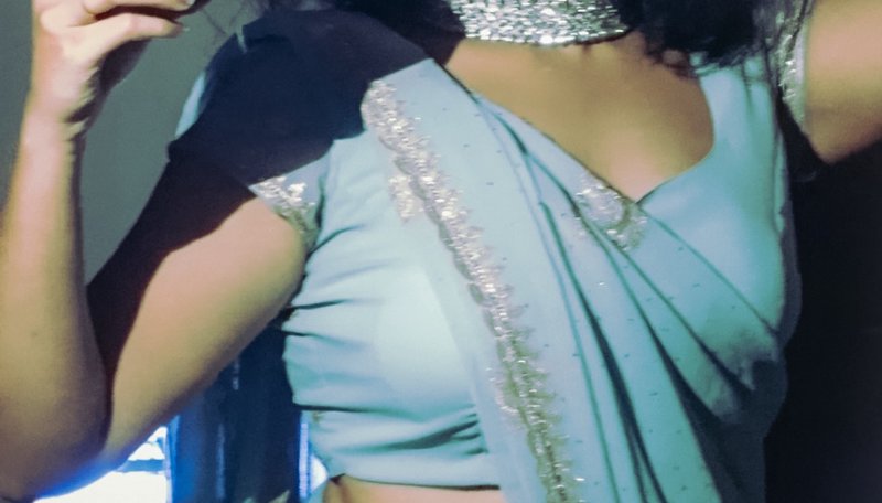 Close-up cropped view of a woman wearing a pale blue embroidered saree and sparkling silver state...