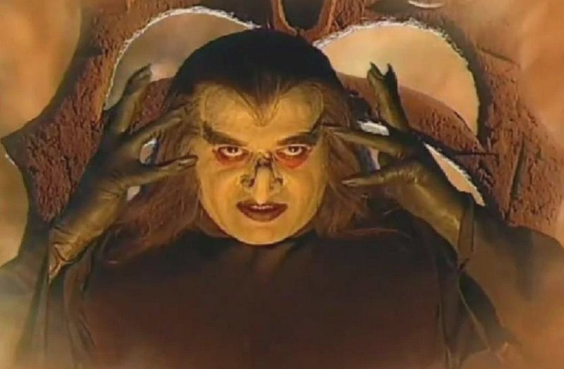 Menacing ghoulish fantasy villain holds clawed hands to his head, staring intensely directly at t...