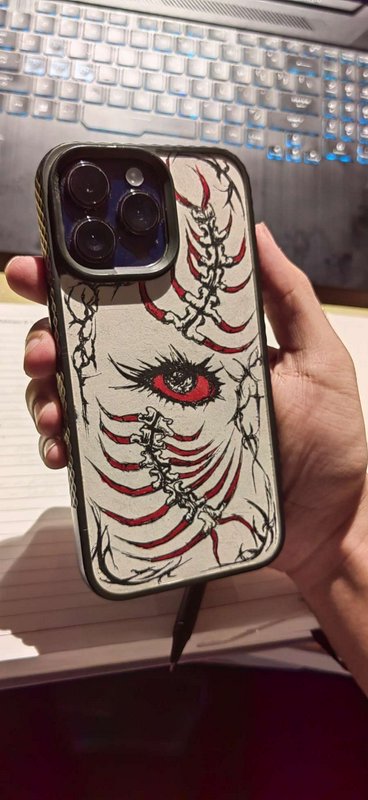 Hand holding a custom iPhone case with hand-drawn gothic skeleton and red eye artwork