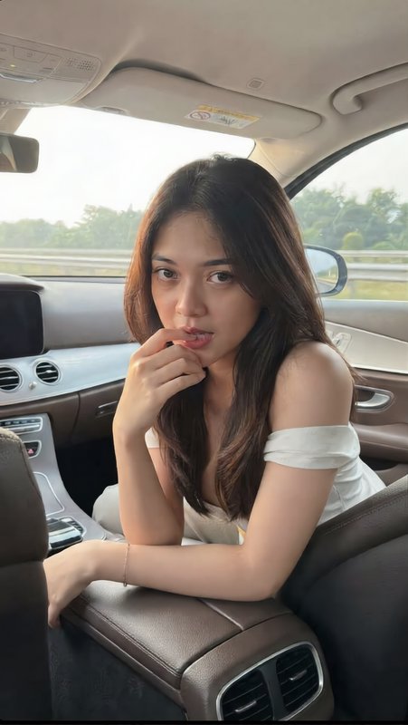 Young woman in a white off-shoulder top posing casually inside a luxury sedan
