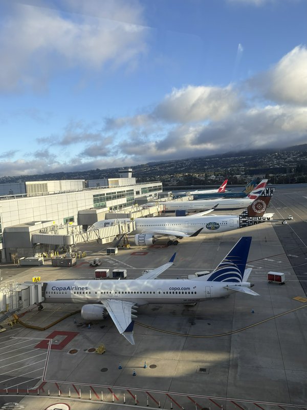 Aerial view of airport tarmac with parked commercial jets at terminal gates, foreground Copa Airlines aircraft under brigh...