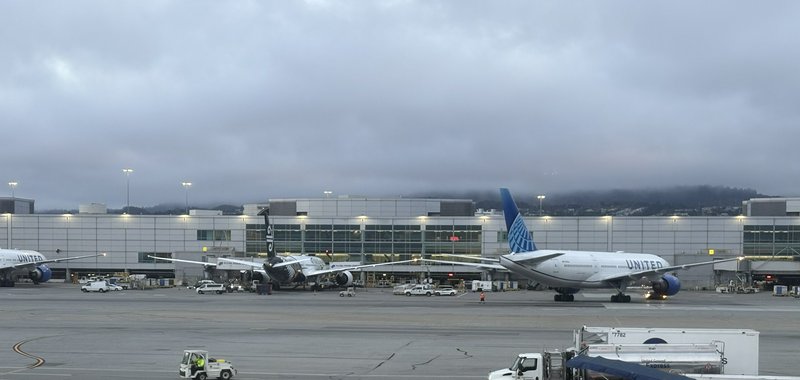 Parked United Airlines and Air New Zealand jets sit on an airport tarmac at a terminal under over...