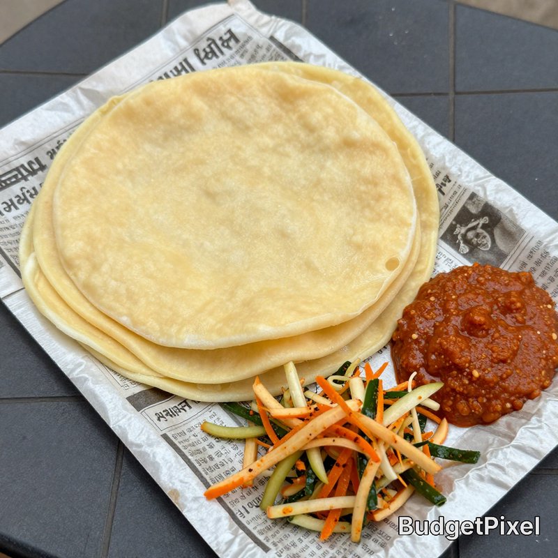 Stack of soft thin flatbreads served with spicy red chutney and pickled vegetable slaw on printed...