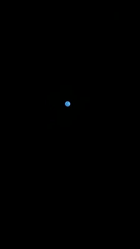 Small glowing pale blue full moon centered against a pitch black featureless night sky
