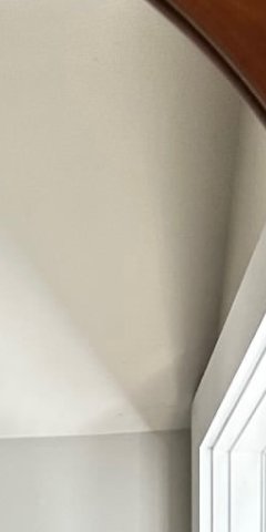 Blurry interior view of a home room corner with beige ceiling, wooden upper trim, and white door ...