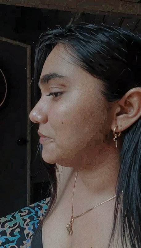 Profile close-up portrait of a woman with long dark hair, dainty gold jewelry, looking left in an...