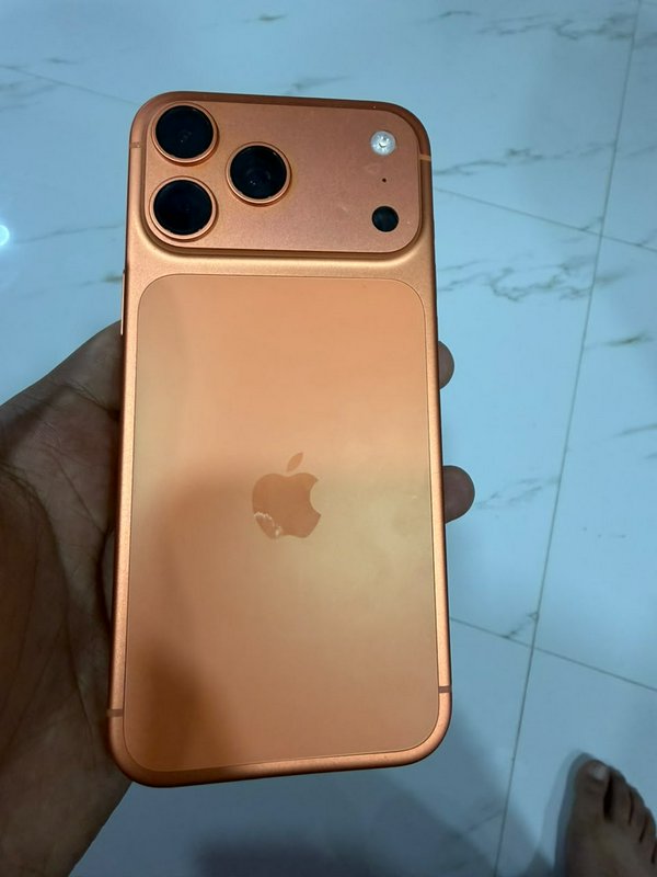 Hand holding a custom metallic copper orange modified iPhone rear with an oversized triple camera...