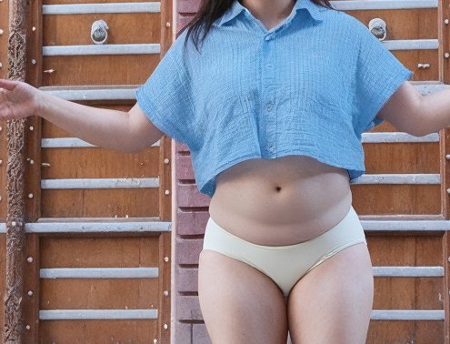Unrecognizable curvy woman in a cropped light blue shirt and cream underwear stands before a carv...
