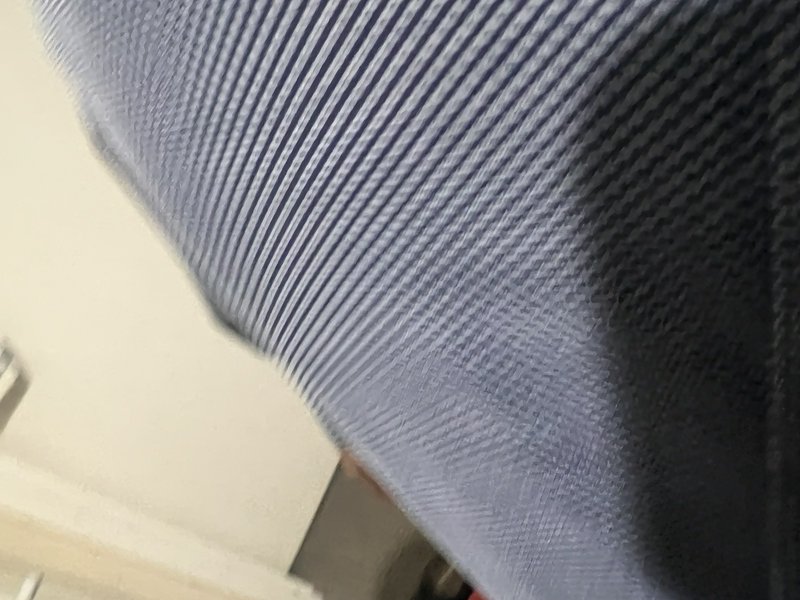 Close up of diagonal striped muted blue woven fabric adjacent to a pale cream interior wall