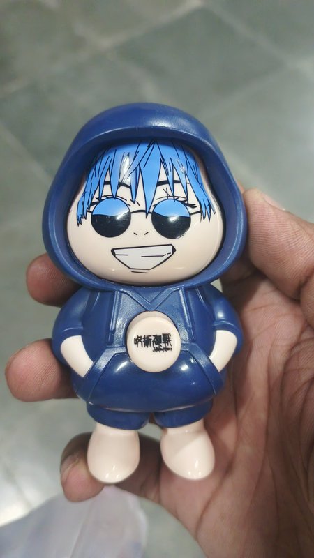 Hand holding chibi Satoru Gojo Jujutsu Kaisen novelty plastic figurine with hooded outfit and log...