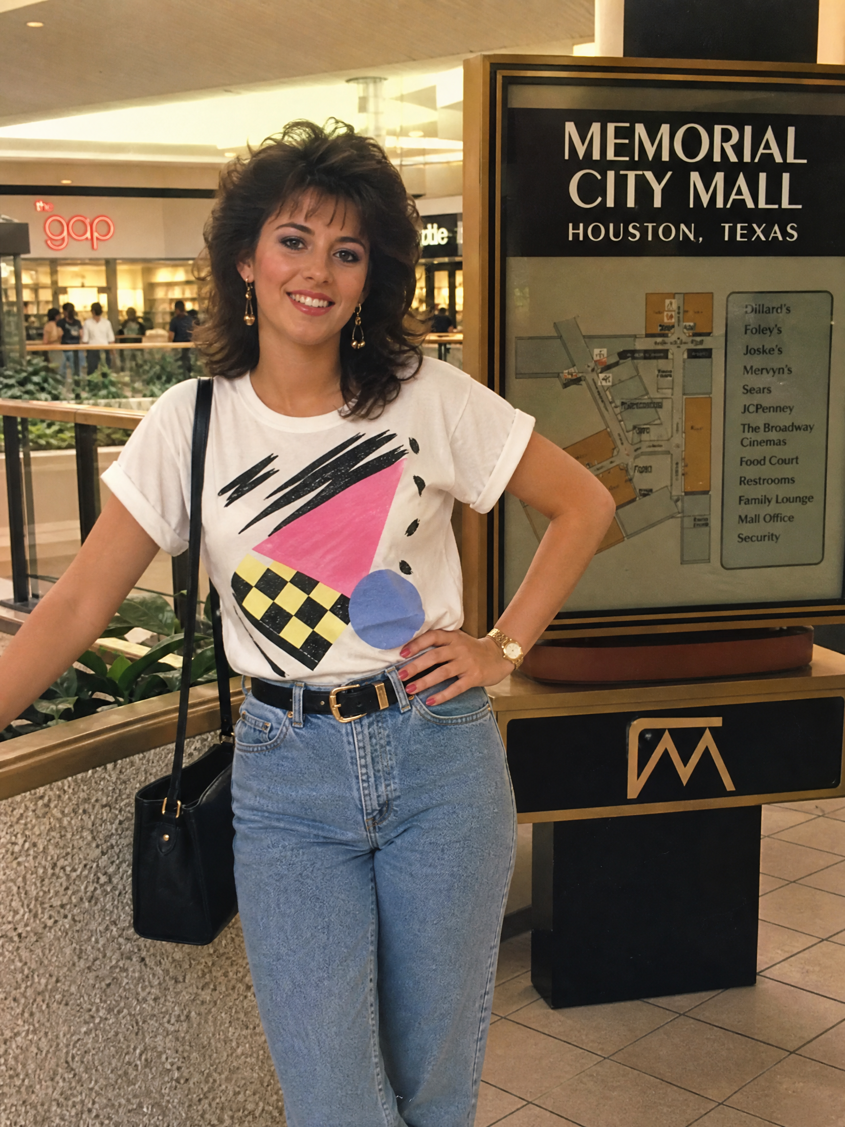 Woman in a geometric print white T-shirt and high-waisted jeans posing at Memorial City Mall, Houston.