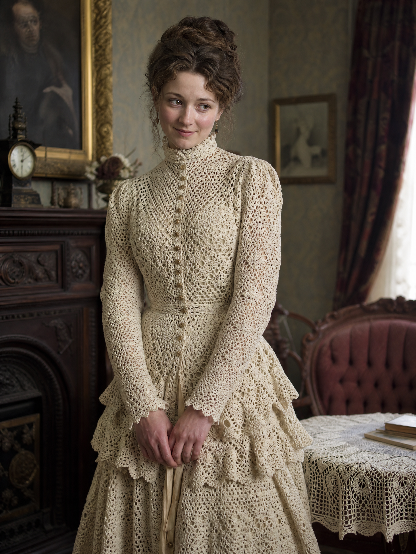 Woman in a cream Victorian crochet lace dress with high collar in a vintage interior.