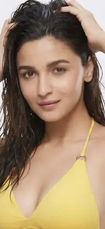 Close-up portrait of Alia Bhatt with wet dark hair, wearing a yellow halter top, hands in her hai...