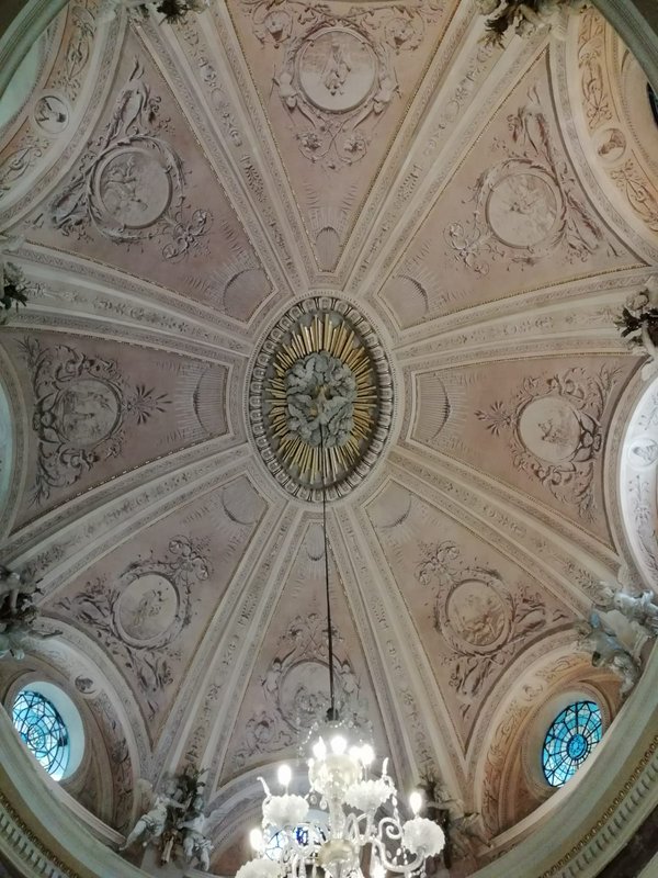 Ornate domed ceiling with gilded centerpiece and chandelier in a historic church.