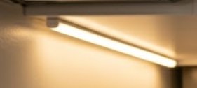 Close-up of a glowing fluorescent light tube casting warm light on a ceiling.