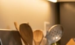 Blurry kitchen scene with wooden spoons and a spatula resting in a utensil holder