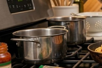 Shiny stainless steel pots simmering on a modern gas stove in a kitchen.