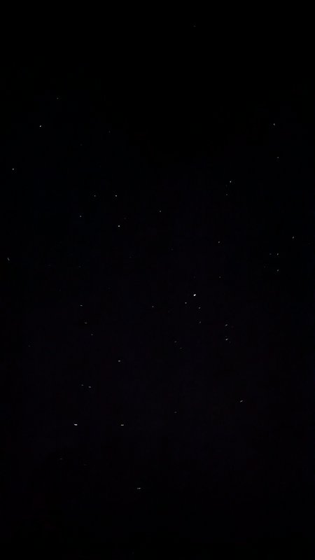 Dark inky night sky dotted with scattered faint tiny white pinprick stars, captured far from urba...