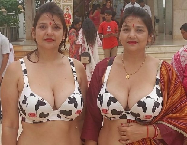 Two women in matching cow-print bras pose outside a temple with other visitors in the background
