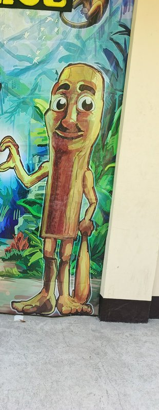Friendly cartoon wooden humanoid mascot waves on a colorful tropical jungle themed event mural ba...
