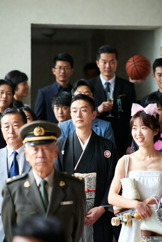 Group of guests at a formal ceremony, with a man in a kimono and a smiling woman in a white dress.