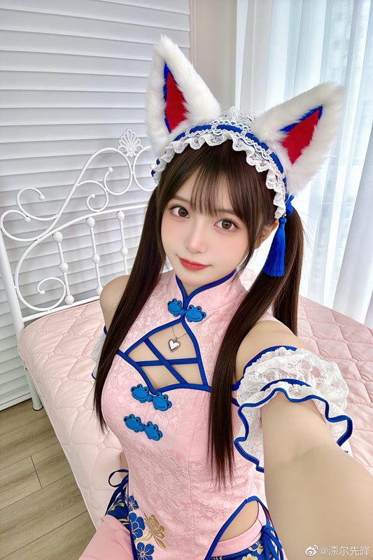 Cosplayer wearing fluffy fox ear headband and pink cheongsam takes a selfie in a sunlit bedroom